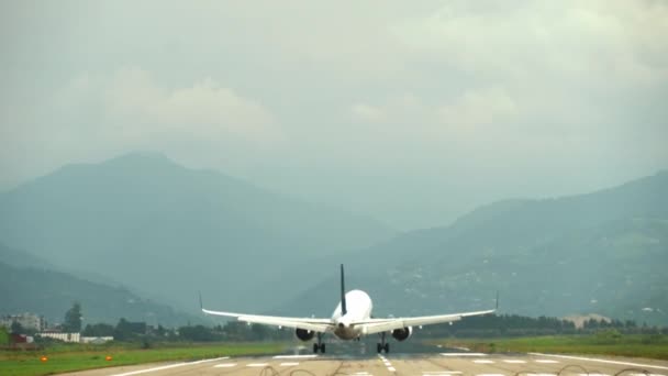 大規模な近代的な旅客飛行機の土地や山や雲の背景に良い晴れた天気で空港に着陸することができます 近代旅客航空輸送 — ストック動画