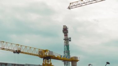 İnşaat halindeki çok katlı apartmanlar. Kentsel alanda gayrimenkul geliştirme. Birçok vinç şantiyede çalışır. Hareket ediyorlar ve inşa ediyorlar..