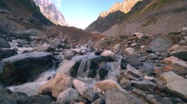 Güneşli bir günde kayalık dağların ve ormanın içinden geçen bir nehir manzarası. Kırsal kesimin güzel bahar manzarası. Dağların arasında çalkantılı bir dağ nehri..