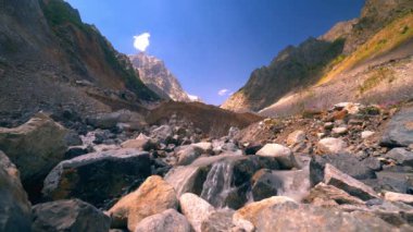 Güneşli bir günde kayalık dağların ve ormanın içinden geçen bir nehir manzarası. Kırsal kesimin güzel bahar manzarası. Dağların arasında çalkantılı bir dağ nehri..