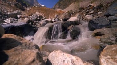 Güneşli bir günde kayalık dağların ve ormanın içinden geçen bir nehir manzarası. Kırsal kesimin güzel bahar manzarası. Dağların arasında çalkantılı bir dağ nehri..