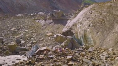 Güneşli bir günde dağların, nehrin, Chalaadi buzulunun güzel manzarası. Dağların çok güzel sonbahar manzarası. Uçurumun kenarında kameraya bakan dört turist. Bir İHA görüntüsü