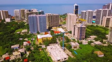 Drone view of construction site, multi-storey buildings under construction against backdrop of sea and large metropolis in Georgia. Batumi. Investment of finance in real estate. Skyscrapers