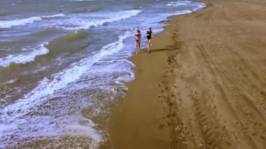 Noel Sahil Tatili Noel Baba Şapkalı ve Bikini 'li Seyahat Kadınları Tropikal plajda kış tatillerinin tadını çıkarın. Kızlar deniz kenarında yürürler ve manzaranın tadını çıkarırlar. Hava veya insansız hava aracı fotoğrafçılığı