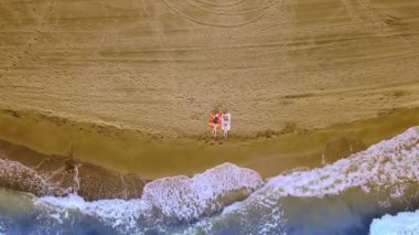 Noel Sahil Tatili Noel Baba Şapkalı Gezgin Kadınlar ve Bikini Tropikal Plajda Kış Tatilinin tadını çıkarın. Kızlar deniz kenarındaki sandalyelere oturur ve şarap kadehlerinin keyfini çıkarırlar. Hava veya İHA saldırısı