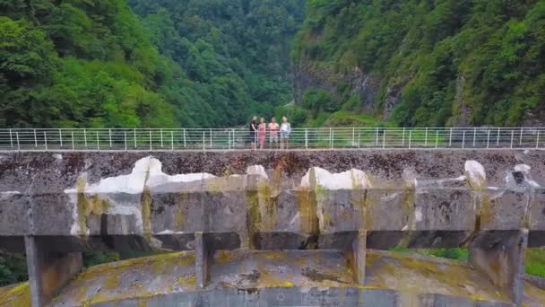 4人で構成される会社は ジョージア州の山や川を背景に峡谷を渡る大きなコンクリートの歩道橋を渡っています 観光客は地域を探索し 古代の橋のドローンの形でランドマーク — ストック動画