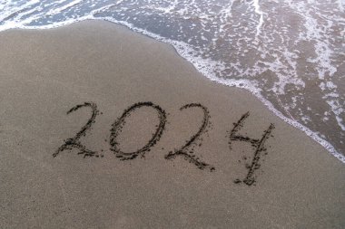 Küçük bir dalgayla kumlu bir sahilde mutlu yıllar 2024 mesajı at. Gelecek Yeni Yıl 2023 'ün soyut arka plan fotoğrafı