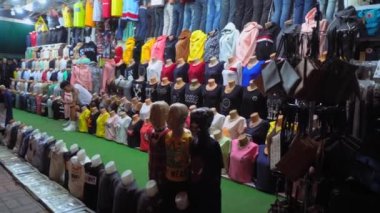 ALANA, TURKEY - 20 Eylül 2022: Alanya 'nın merkezindeki turist mekanında kıyafet mağazası. Satıcı tezgahın ortasında oturuyor. Ucuz giysi pazarı. Manikürlü tişört ve pantolon..