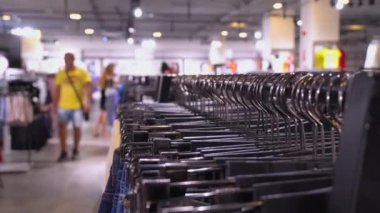 Giyim mağazası. Askısı ve kotu olan bir stil. Odaklanamayan alıcıların arka planında. Mesaj için yer. Büyük bir süpermarket ya da içinde bir şeyler olan bir butik. Sıraya dizilmiş şeyler asılır.