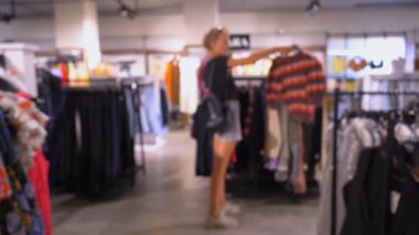 Odaklan, odaklan. Şirin bir kadın giyim mağazasından kıyafet seçiyor. Giyim mağazasında bir şey bulmuş. Alışveriş, moda, satış konsepti. Kafkas sarışını. Deponun genel planı.
