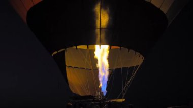 Balonun gece uçmak için şişerken yakın çekimi, balonu hava kapadokyasına kaldırmak için yakıcı ateş, hindi. İnsanların balonlarla fotoğraf çektirmek için toplandığı Goreme 'e park et..