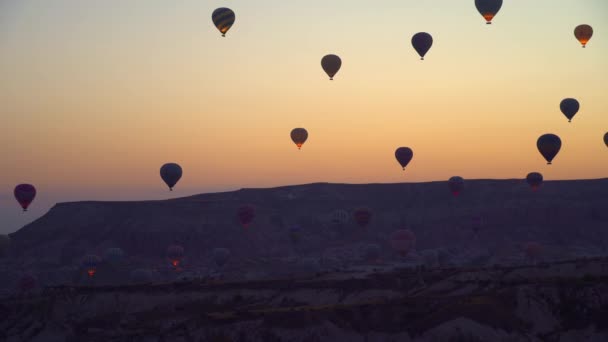 雲のない山とピンクの空の背景に風船の夜明け トルコのカッパドキアの空の風船 夜明けに空を飛ぶ小さな風船の多くは — ストック動画