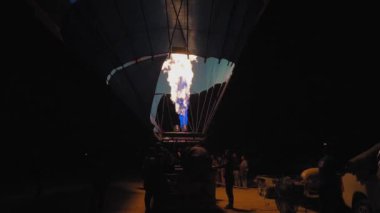 Balonun gece uçmak için şişerken yakın çekimi, balonu hava kapadokyasına kaldırmak için yakıcı ateş, hindi. İnsanların balonlarla fotoğraf çektirmek için toplandığı Goreme 'e park et..