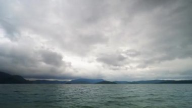 Gürcistan 'daki Tkibul gölündeki bulutların yavaş çekim incelemesi. Dağın arka planında. Bulutlar çabucak kaybolur ve güneş batar. Alacakaranlık geceye dönüşüyor.