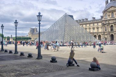 Paris, France - May 26, 2022: Front of Louvre Museum with motion blurred tourists and children playing in foreground