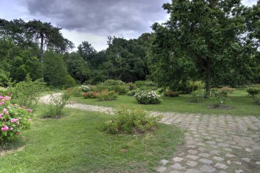 Paris, France - May 29, 2022: View of Chateau de Bagatelle across wild garden with flowers, trees and tourists