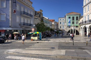 Aveiro, Portekiz - 14 Ağustos 2022: Önünde kaldırım taşlı yol ve yaya geçidi olan çok sayıda yaya ve park etmiş mobiletlerin olduğu sokak sahnesi