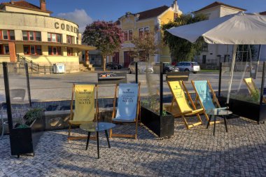 Aveiro, Portekiz - 14 Ağustos 2022: Ateşli Ağaç Tonik Suyu 'nun arkasına kazılı olduğu barda bağlanmamış güverte sandalyeleri