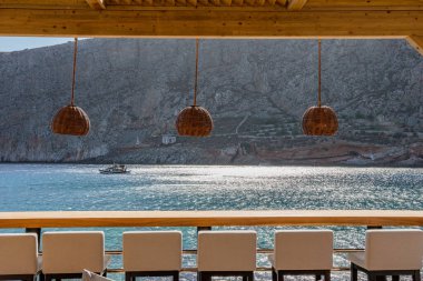 Modern dekorasyon, rahatlatıcı bir sandalyesi ve yaz aylarında Yunan denizi manzaralı ahşap mobilyaları olan asgari tarz..