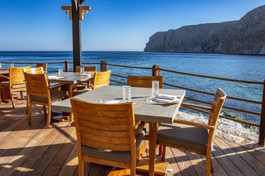 Modern dekorasyon, rahatlatıcı bir sandalyesi ve yaz aylarında Yunan denizi manzaralı ahşap mobilyaları olan asgari tarz..