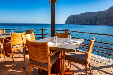 Modern dekorasyon, rahatlatıcı bir sandalyesi ve yaz aylarında Yunan denizi manzaralı ahşap mobilyaları olan asgari tarz..