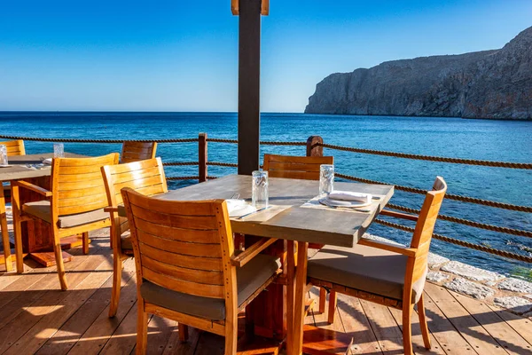 Modern dekorasyon, rahatlatıcı bir sandalyesi ve yaz aylarında Yunan denizi manzaralı ahşap mobilyaları olan asgari tarz..