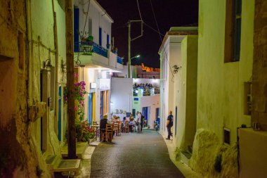 Geceleri Chora köyünün sokaklarında yürüyen insanların olduğu mimari binalar. Kythera adasındaki pitoresk Chora köyünün şehir fotoğrafçılığı.