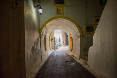 Geceleri Chora köyünün sokaklarında yürüyen insanların olduğu mimari binalar. Kythera adasındaki pitoresk Chora köyünün şehir fotoğrafçılığı.
