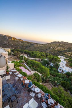 Yunanistan 'ın Kythira adasındaki Chora köyünün sokaklarında yürüyen insanların olduğu mimari binalar. Kythera adasındaki pitoresk Chora köyünün şehir fotoğrafçılığı.