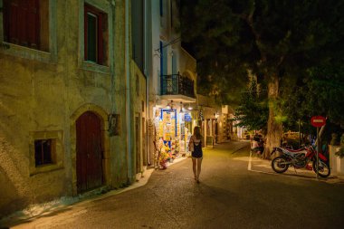 Geceleri Chora köyünün sokaklarında yürüyen insanların olduğu mimari binalar. Kythera adasındaki pitoresk Chora köyünün şehir fotoğrafçılığı.