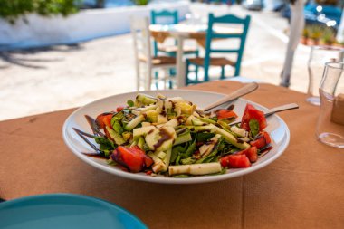 Yunanistan 'ın Kythera adasındaki Avlemonas köyündeki geleneksel bir Yunan restoranında ahşap masada Yunan salatası.
