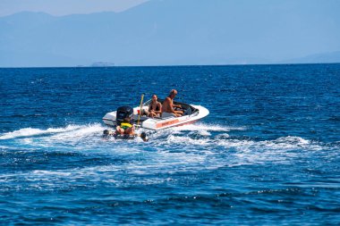 Tourists enjoy inflatable towable rides at Koukounaries beach in Skiathos island, Sporades, Greece