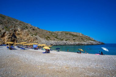The beautiful pebbled beach of Chalkos in Kythera. Amazing scenery with crystal clear water and a small rocky gulf in Kythera island against a deep blue summer sky