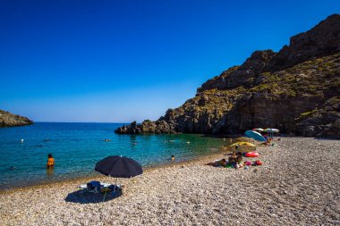 Kythera 'daki Chalkos' un güzel çakıl taşlı plajı. Kristal berrak su ve Kythera adasında küçük kayalık bir körfez ile harika bir manzara derin mavi bir yaz gökyüzüne karşı.