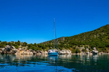 Peristera, Alonissos, Yunanistan 'ın ünlü gemi enkazı yakınlarındaki Peristera adasında demirli bir yelkenlinin güzel manzarası