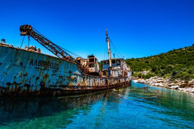 Alonissos, Sporades, Yunanistan yakınlarındaki Peristera adasında eski bir kargo gemisinin paslı gemi enkazının yanında.