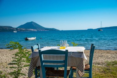 Tipik Yunan sahil tavernası masası Pylos şehri, Messinia, Yunanistan, Avrupa yakınlarındaki Gialova 'da deniz kıyısında ahşap sandalyelerle