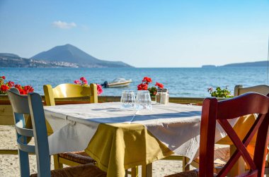 Typical Greek seaside tavern table with wooden chairs by the sea coast in Gialova near Pylos city, Messinia, Greece, Europe