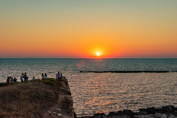 Tourists and visitors gaze the beautiful sunset sky bhehind the Casthle of Methoni, Messenia, Greece