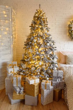 Altında hediyeler olan Noel ağacıyla süslenmiş güzel bir holdiay odası.