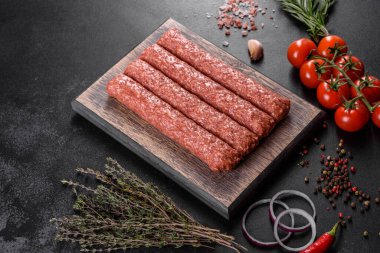 Koyu beton arka planda baharat ve otlarla ızgara kebap için taze çiğ kıyma.