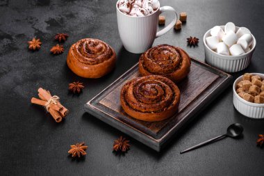 Baharatlı taze tarçınlı rulo ve siyah arka planda kakao. Cinnabon çörekleri. İsveç kahvaltısı.