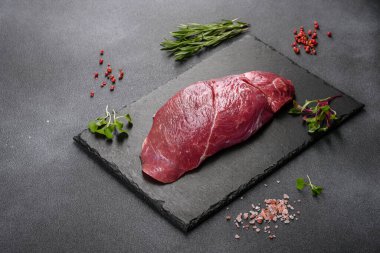 Çiğ Chuck rulo bifteği, otlar ve kesme tahtasında tuz. Gri arkaplan