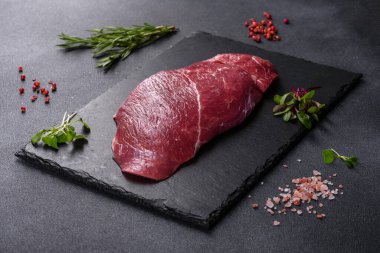 Çiğ Chuck rulo bifteği, otlar ve kesme tahtasında tuz. Gri arkaplan