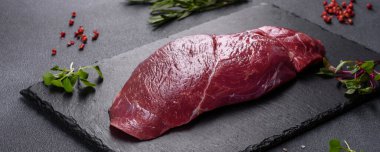 Çiğ Chuck rulo bifteği, otlar ve kesme tahtasında tuz. Gri arkaplan