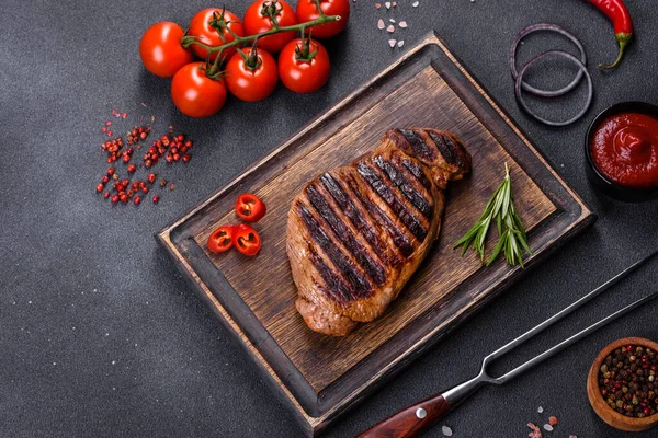 Cooked grilled Chuck eye roll steak on a chopping Board. Dark background