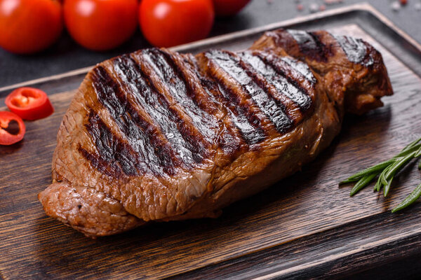 Cooked grilled Chuck eye roll steak on a chopping Board. Dark background