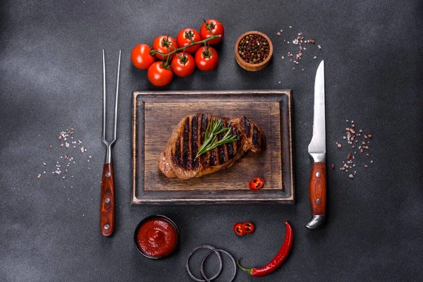 Cooked grilled Chuck eye roll steak on a chopping Board. Dark background