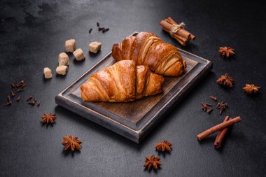 Delicious fresh crispy croissants on a dark concrete background. Tasty breakfast