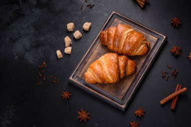 Delicious fresh crispy croissants on a dark concrete background. Tasty breakfast